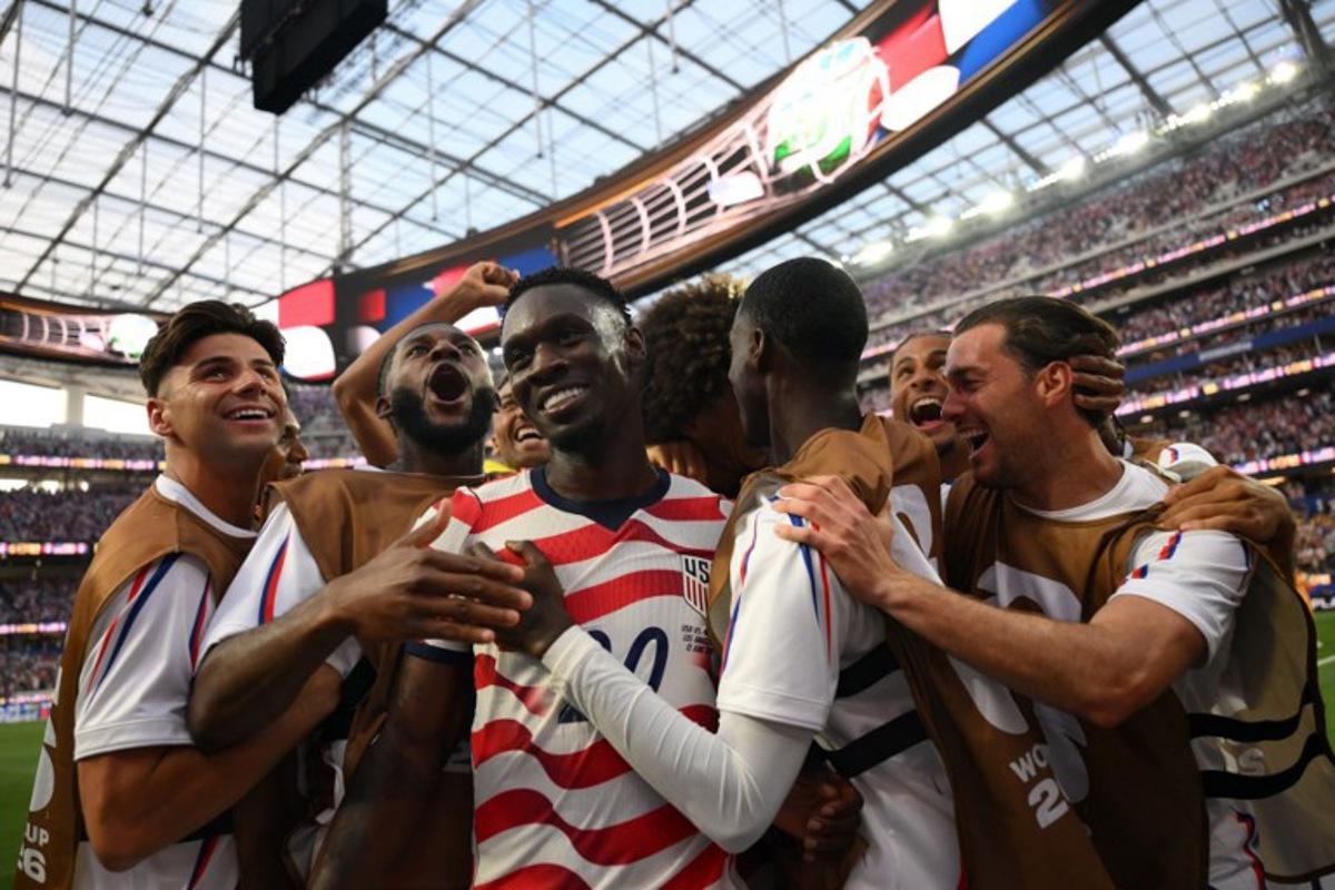 US forward #20 Folarin Balogun (c) celebrates with teammates after scoring his team's third goal during the 2026 World Cup Group D football match between USA and Paraguay at the Los Angeles Stadium in Inglewood on June 12, 2026. Patrick T. Fallon / AFP
