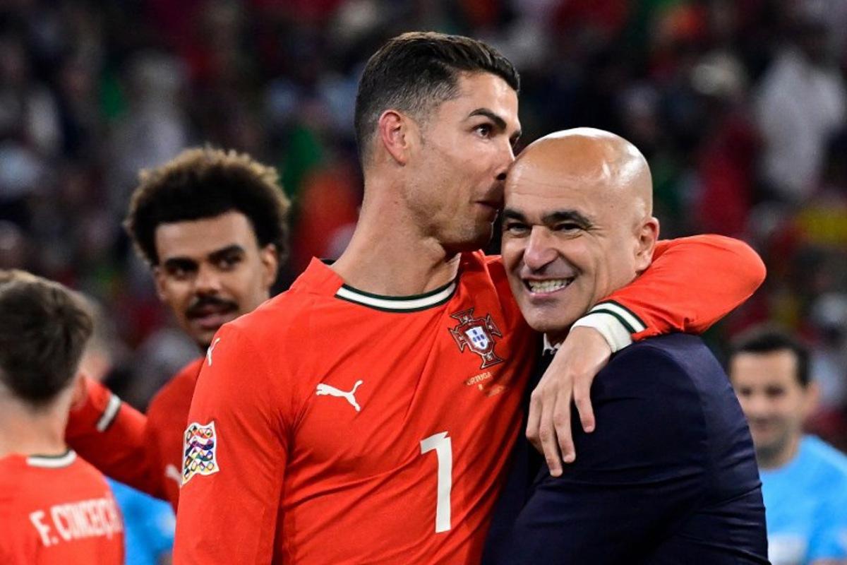 Portugal's forward #07 Cristiano Ronaldo and Portugal's Spanish head coach Roberto Martinez celebrate winning the UEFA Nations League final football match between Portugal and Spain in Munich, southern Germany on June 8, 2025. John MACDOUGALL / AFP