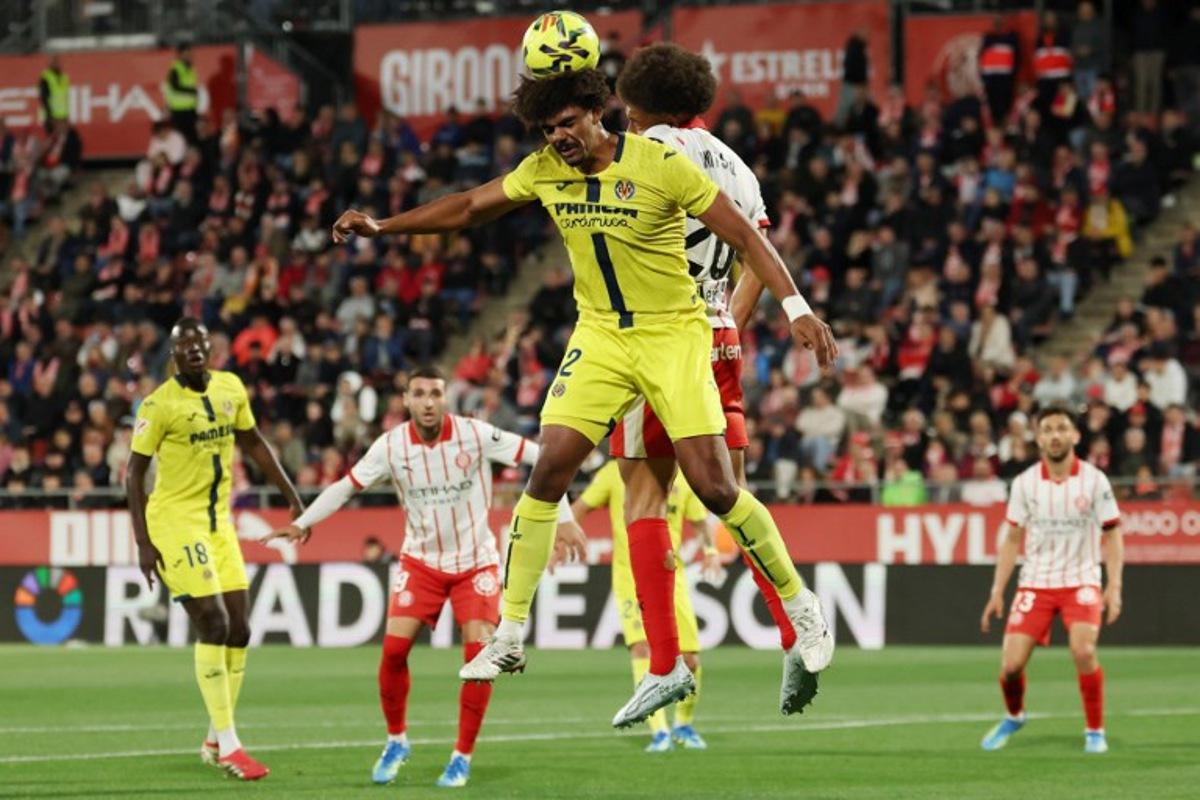 Villarreal's Portuguese defender #12 Renato Veiga wins a header against Girona's Belgian defender #20 Axel Witsel during the Spanish league football match between Girona FC and Villarreal CF at Montilivi Stadium in Girona on April 6, 2026. Lluis GENE / AFP