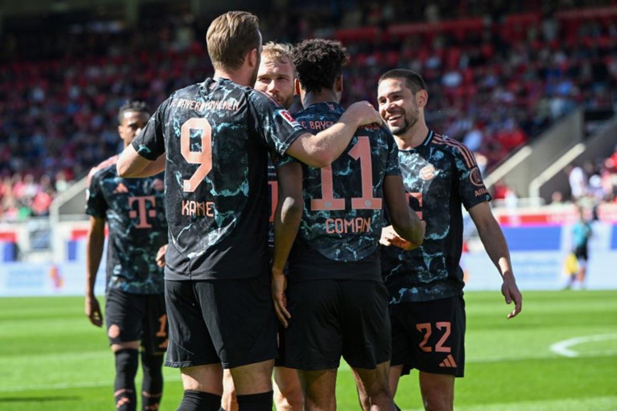 Bayern Munich's French forward #11 Kingsley Coman celebrates scoring the 0-3 goal with his teammates including Bayern Munich's English forward #09 Harry Kane (L) during the German first division Bundesliga football match between Heidenheim and Bayern Munich in Heidenheim, southern Germany on April 19, 2025. THOMAS KIENZLE / AFP