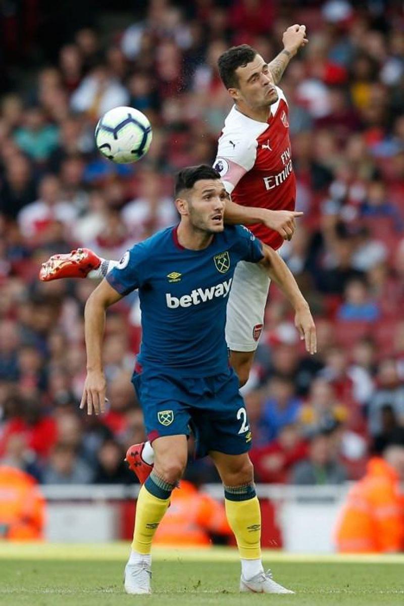 Arsenal's Swiss midfielder Granit Xhaka (R) jumps over West Ham United's Spanish striker Lucas Perez (L) during the English Premier League football match between Arsenal and West Ham United at the Emirates Stadium in London on August 25, 2018. Ian KINGTON / AFP RESTRICTED TO EDITORIAL USE. No use with unauthorized audio, video, data, fixture lists, club/league logos or 'live' services. Online in-match use limited to 120 images. An additional 40 images may be used in extra time. No video emulation. Social media in-match use limited to 120 images. An additional 40 images may be used in extra time. No use in betting publications, games or single club/league/player publications.