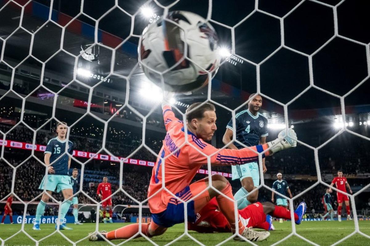 Switzerland's forward #7 Breel Embolo (Bottom) scores his team's second goal past Germany's goalkeeper #01 Oliver Baumann and Germany's defender #04 Jonathan Tah during the international friendly football match between Switzerland and Germany at St. Jakob-Park in Basel, Switzerland on March 27, 2026. Fabrice COFFRINI / AFP