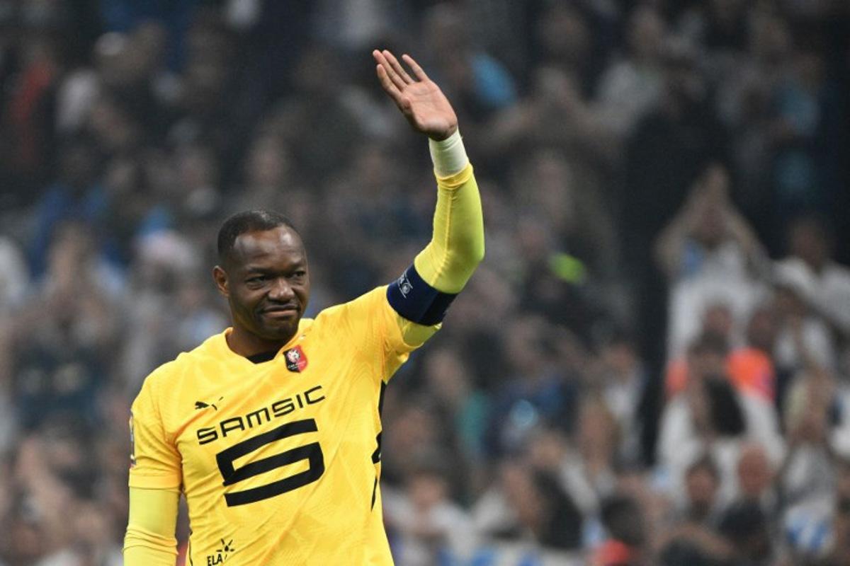 Rennes' French goalkeeper #30 Steve Mandanda salutes the OM supporters after receiving the captain's armband from Marseille's Argentinian defender #05 Leonardo Balerdi at the end of their ligue 1 football match Olympic of Marseille (OM) against stade Rennais at the Velodrome stadium, in Marseille on May 17, 2025. Christophe SIMON / AFP