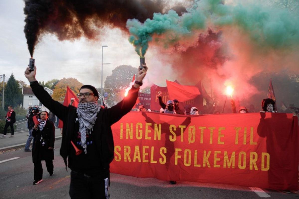 Protesters light flares as they demonstrate in solidarity with the Palestinian people and against Israel, close to the Ullevaal Stadium in Oslo, Norway, on October 11, 2025, prior to the 2026 World Cup qualifying football match between Norway and Israel. Javad Parsa / NTB / AFP