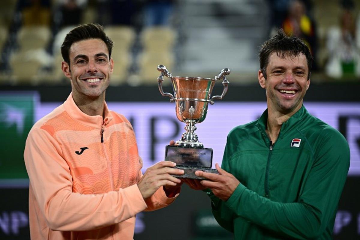 Spain's Marcel Granollers (L) and Argentina's Horacio Zeballos hold their trophy after winning their men's doubles final match against Britain's Joe Salisbury and Britain's Neal Skupski on day 14 of the French Open tennis tournament on Court Philippe-Chatrier at the Roland-Garros Complex in Paris on June 7, 2025. JULIEN DE ROSA / AFP