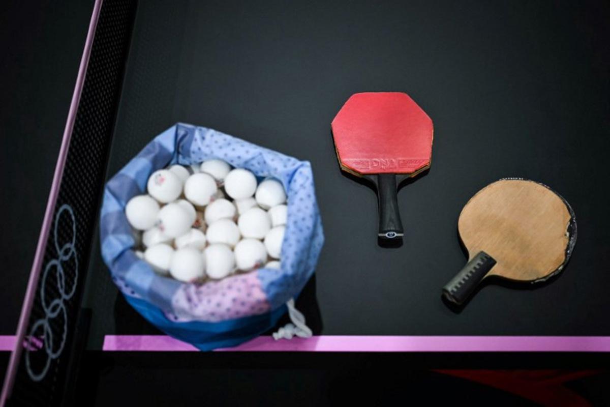 A plastic bag full of table tennis balls is pictured next to tennis table rackets during the training sessions on the third day of the table tennis competition at the Paris 2024 Olympic Games at the South Paris Arena in Paris on July 29, 2024. Ben STANSALL / AFP