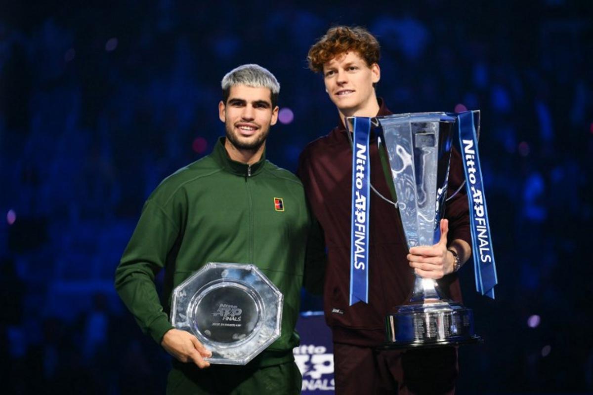 Italy's Jannik Sinner (R) and Spain's Carlos Alcaraz pose with their trophies at the end of the men's single final match at the ATP Finals tennis tournament, in Turin, on November 16, 2025. Marco BERTORELLO / AFP
