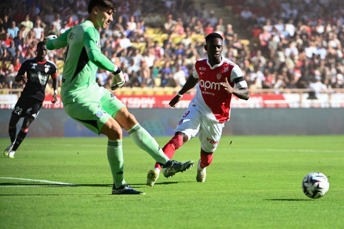 Strasbourg's Belgian goalkeeper #39 Mike Penders (L) shoots the ball next to Monaco's American forward #09 Folarin Balogun (R) during the French L1 football match between AS Monaco and RC Strasbourg Alsace at the Louis II Stadium in the Principality of Monaco on August 31, 2025. FREDERIC DIDES / AFP