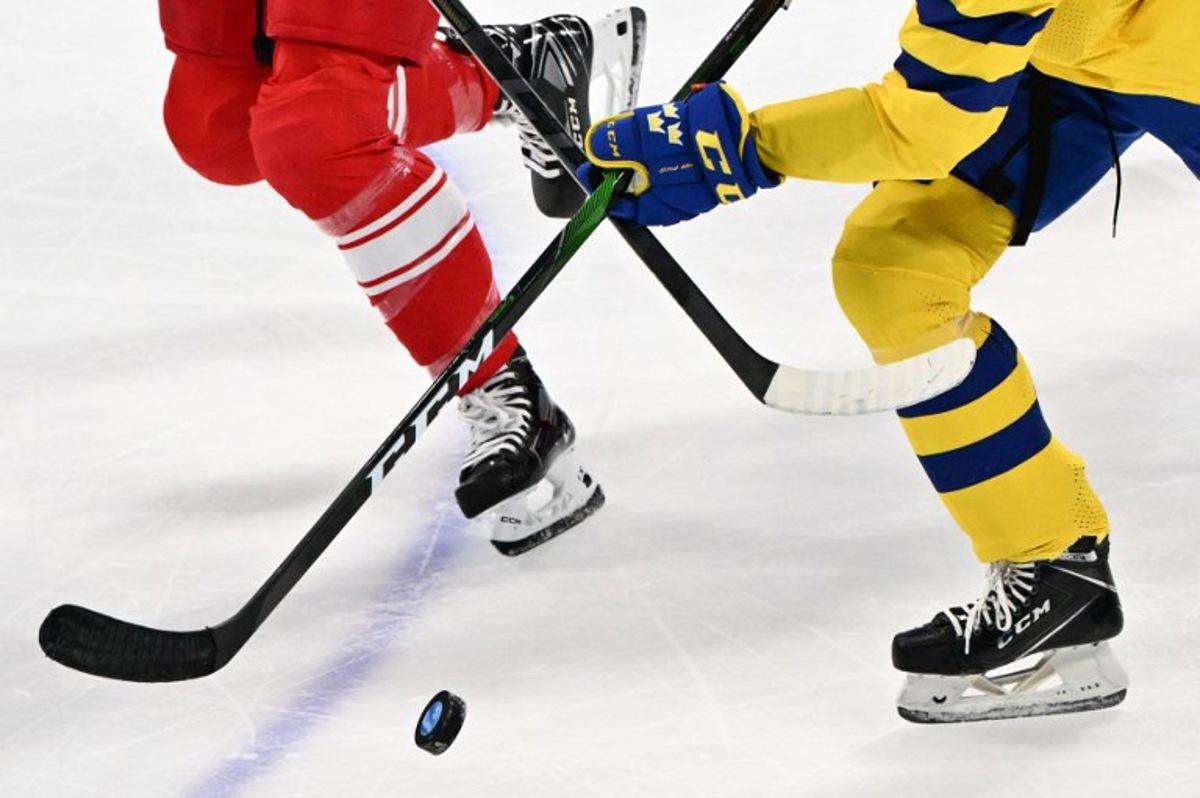 Sweden's Jessica Adolfsson vies for the puck with Denmark's Josefine Jakobsen during their women's preliminary round group B match of the Beijing 2022 Winter Olympic Games ice hockey competition, at the Wukesong Sports Centre in Beijing on February 8, 2022. ANTHONY WALLACE / AFP